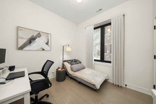 bedroom with visible vents, baseboards, and wood finished floors