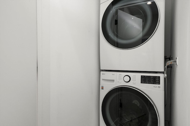 clothes washing area featuring stacked washer and dryer and laundry area