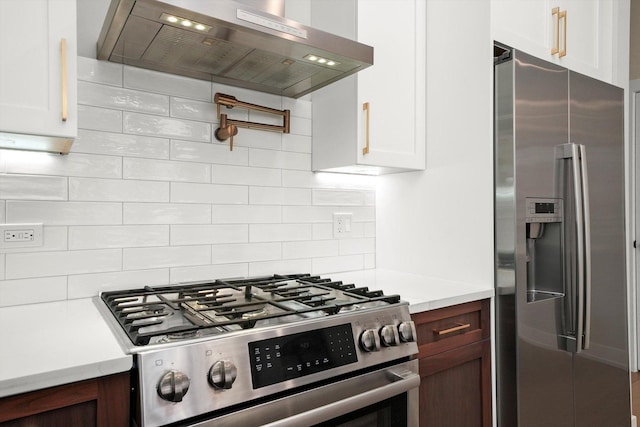 kitchen featuring wall chimney range hood, light countertops, backsplash, and stainless steel appliances