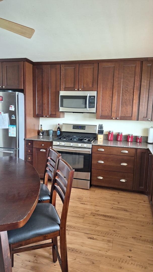 1344 Jeffery Dr, Homewood, IL 60430 - kitchen with dark brown cabinetry, light wood-style floors, and appliances with stainless steel finishes