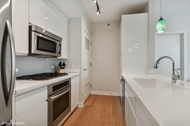 505 N Mcclurg Ct Unit 1801, Chicago, IL 60611 - kitchen with stainless steel appliances, a sink, white cabinetry, light wood-type flooring, and light countertops