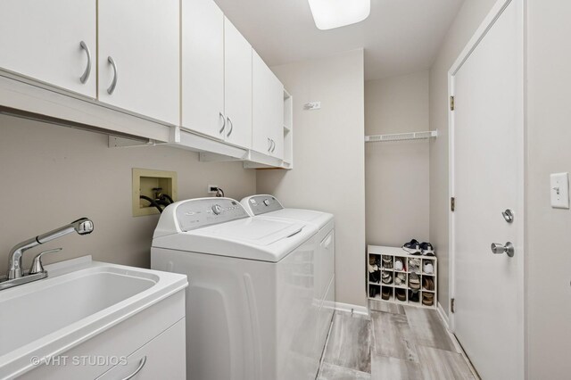 clothes washing area with cabinet space, separate washer and dryer, a sink, and light wood-style floors
