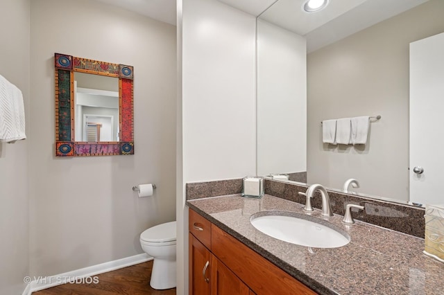 bathroom with toilet, baseboards, wood finished floors, and vanity