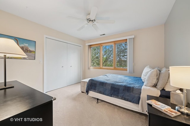 bedroom with visible vents, a ceiling fan, a closet, and light carpet