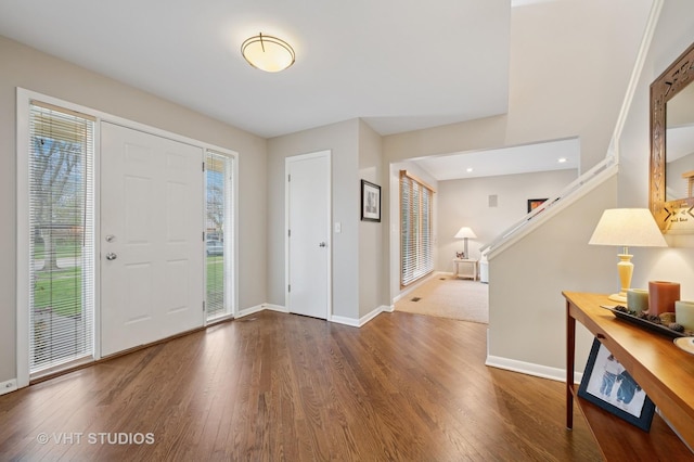 foyer featuring baseboards, stairs, and wood finished floors