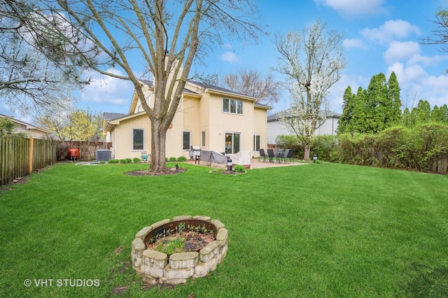 rear view of property featuring a lawn, central AC unit, a fenced backyard, and a patio area