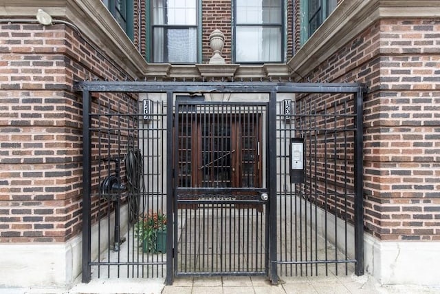 entrance to property with brick siding, fence, and a gate