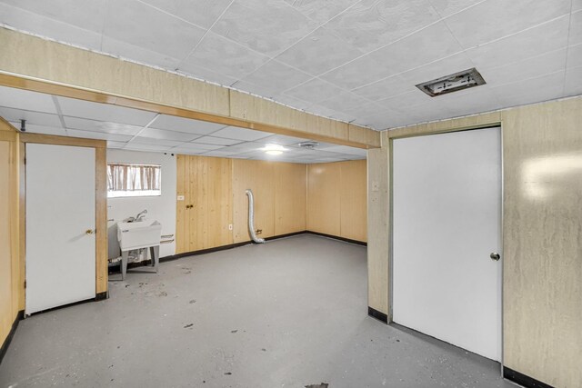 basement featuring a paneled ceiling and a sink