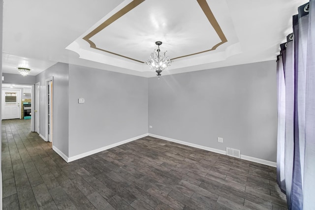 unfurnished room featuring baseboards, visible vents, a chandelier, and a tray ceiling