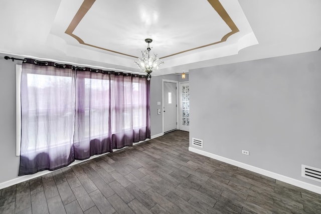 unfurnished room featuring a tray ceiling, a chandelier, visible vents, and dark wood-style flooring