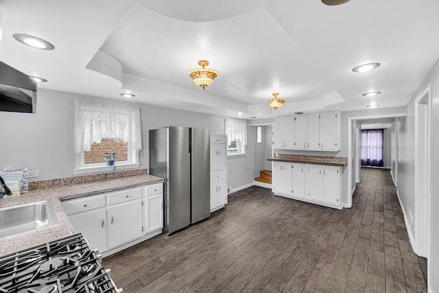 kitchen featuring white cabinets, a sink, stainless steel appliances, and a raised ceiling