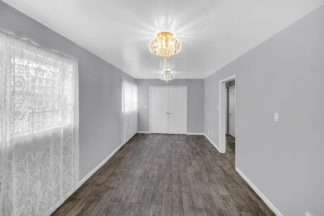 interior space with a closet, an inviting chandelier, dark wood-style flooring, and baseboards