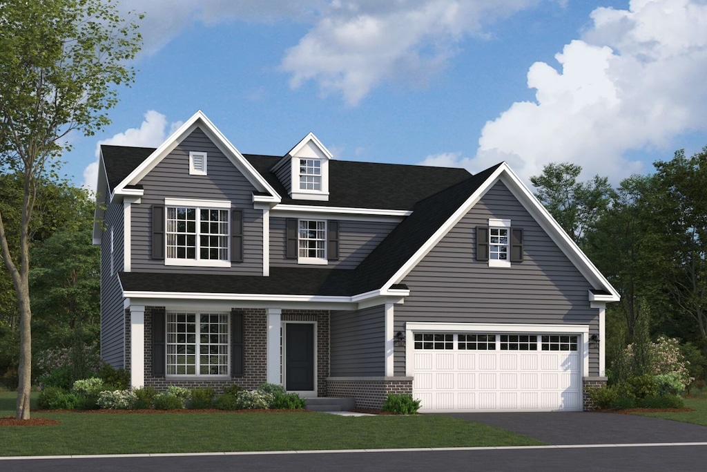 view of front of house with brick siding, driveway, an attached garage, and a front lawn