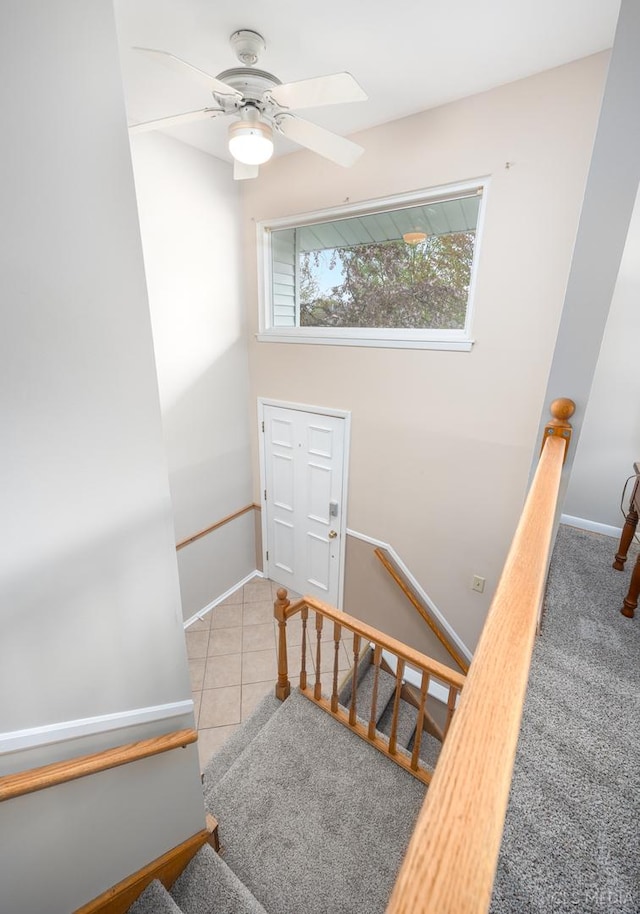 staircase featuring a ceiling fan, tile patterned floors, and baseboards