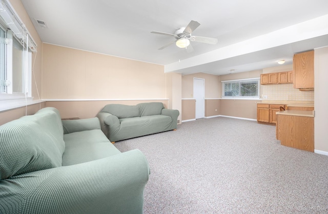 living area featuring ceiling fan, light carpet, and baseboards
