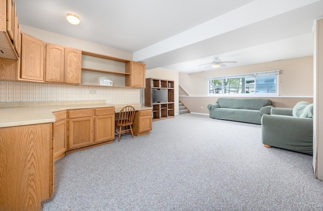living room featuring light colored carpet, a ceiling fan, and stairs