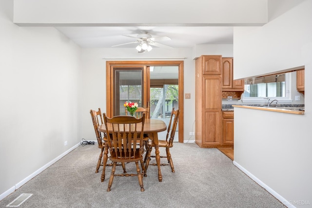 dining space featuring light carpet, baseboards, and ceiling fan