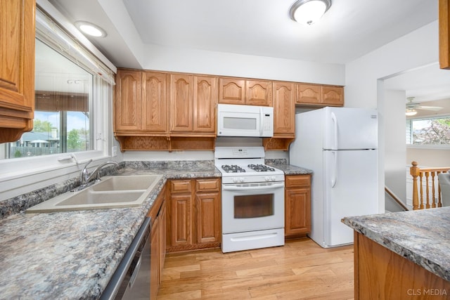 kitchen featuring white appliances, a sink, light wood-style flooring, and brown cabinetry