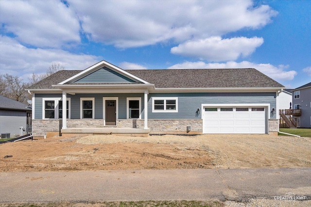 view of front facade featuring an attached garage, stone siding, dirt driveway, and a porch