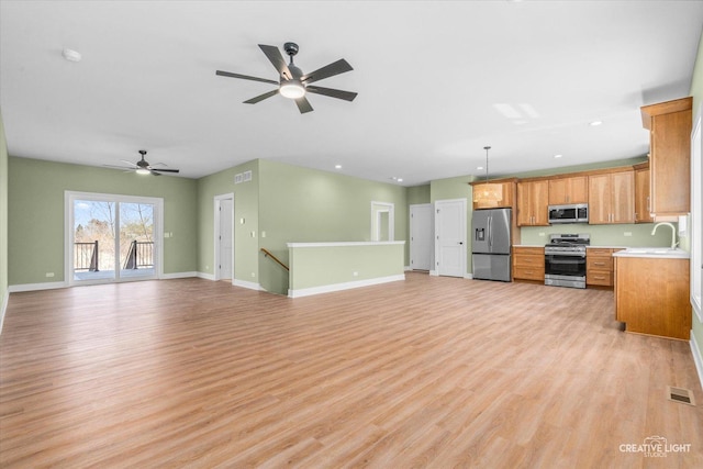 unfurnished living room with visible vents, a ceiling fan, a sink, baseboards, and light wood-style flooring