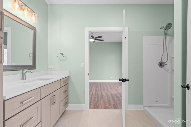 full bath featuring baseboards, vanity, a shower, and ceiling fan