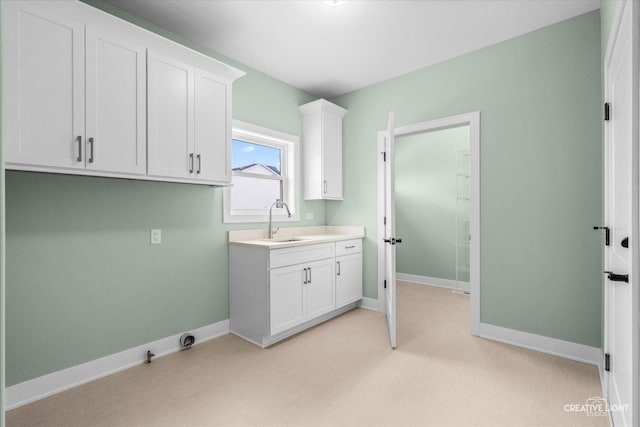 laundry area featuring baseboards and a sink
