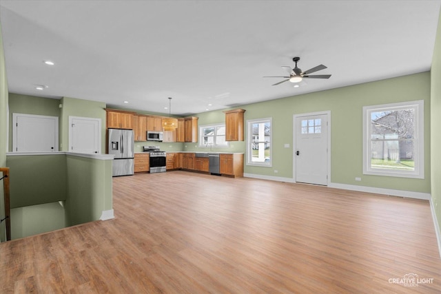 kitchen with stainless steel appliances, light countertops, light wood-type flooring, decorative light fixtures, and baseboards