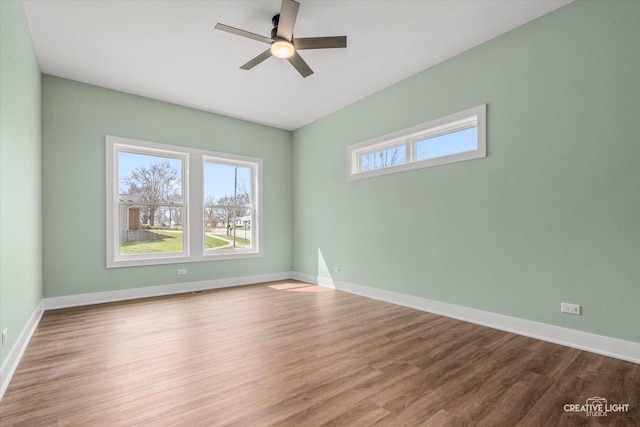 spare room featuring wood finished floors, a ceiling fan, and baseboards