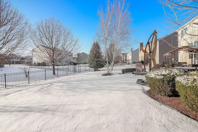 snowy yard featuring a residential view and fence
