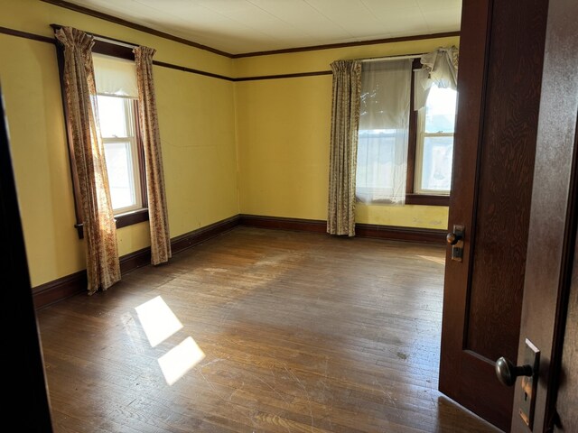 unfurnished room with hardwood / wood-style floors, baseboards, and ornamental molding