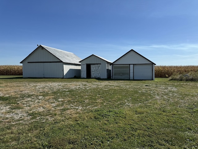 exterior space featuring a garage, a front yard, an outdoor structure, and an outbuilding