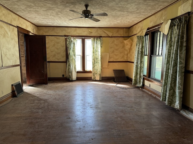 unfurnished room with ceiling fan, a textured ceiling, ornamental molding, wood finished floors, and baseboards