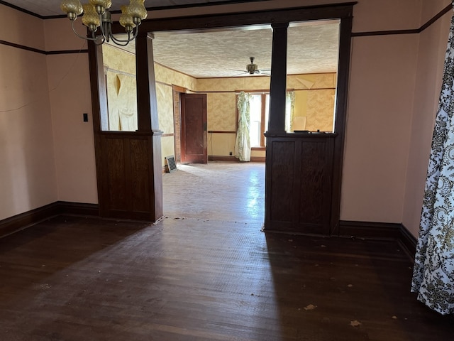 unfurnished dining area featuring baseboards, wallpapered walls, ornamental molding, ceiling fan with notable chandelier, and wood finished floors