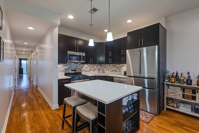 kitchen featuring light wood finished floors, light countertops, decorative backsplash, and appliances with stainless steel finishes
