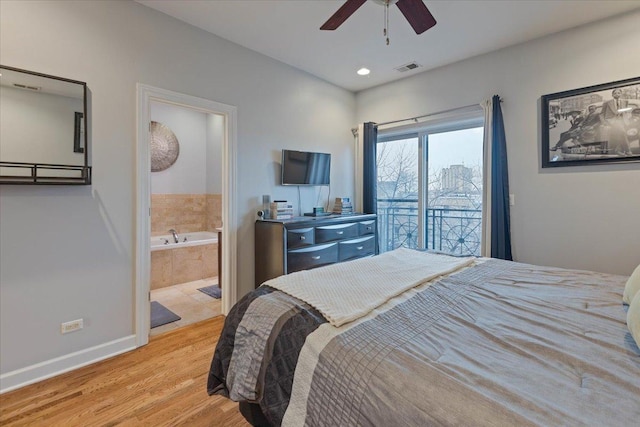 bedroom featuring visible vents, baseboards, ensuite bath, wood finished floors, and access to outside