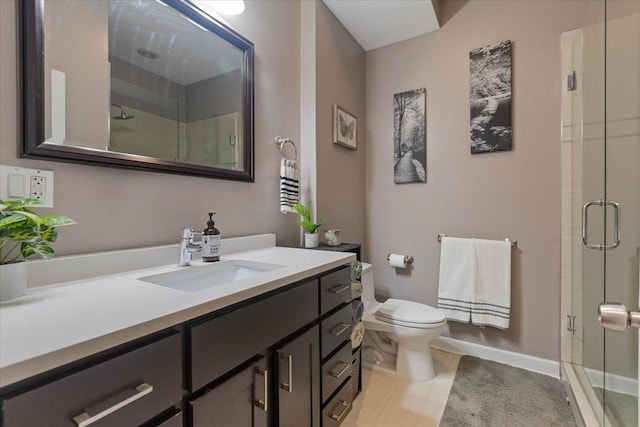 full bathroom featuring toilet, vanity, baseboards, and a stall shower
