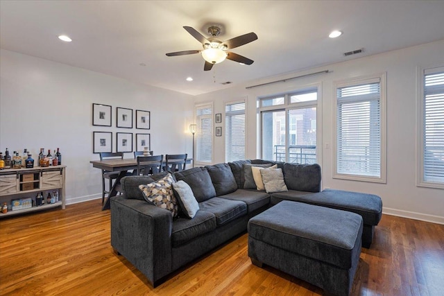 living area with visible vents, ceiling fan, wood finished floors, and baseboards