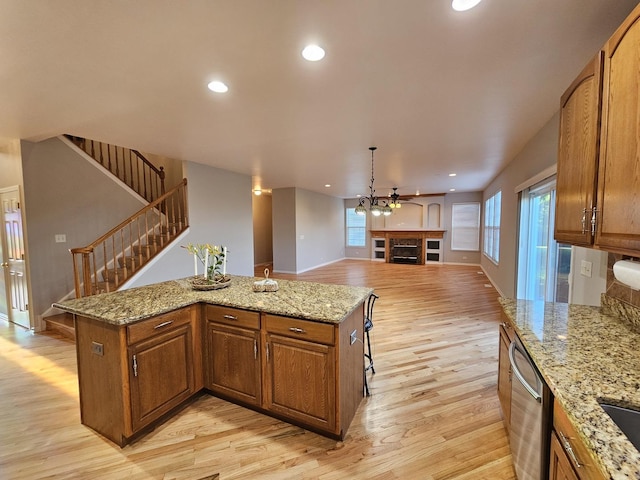 127 Charleston Ln, Gilberts, IL 60136 - kitchen with a fireplace, stainless steel dishwasher, light wood-style floors, brown cabinets, and a kitchen island