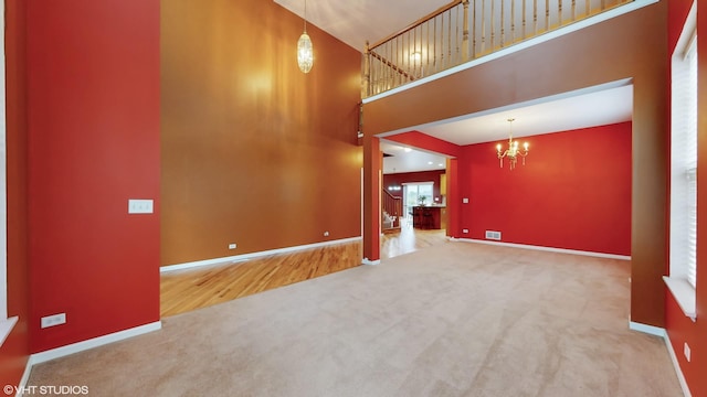 127 Charleston Ln, Gilberts, IL 60136 - unfurnished living room with carpet floors, a high ceiling, a chandelier, and baseboards