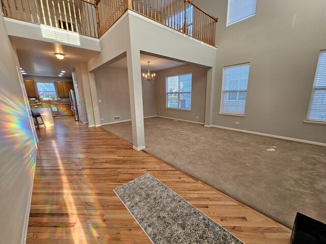 127 Charleston Ln, Gilberts, IL 60136 - unfurnished living room with a chandelier, a high ceiling, wood finished floors, and carpet flooring