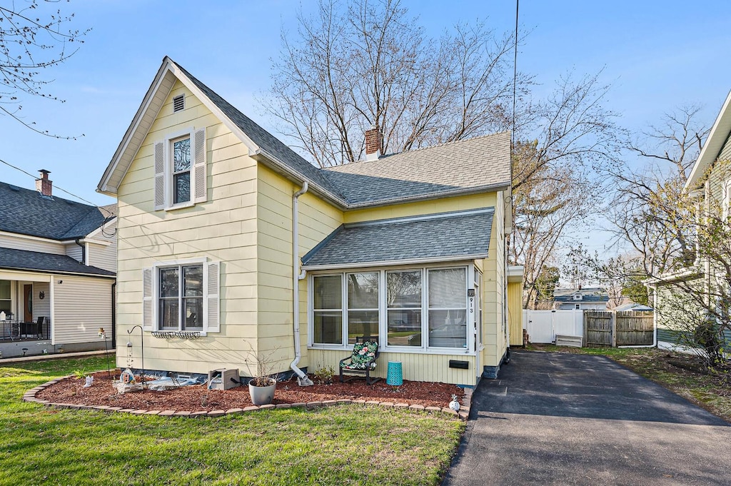 913 Gleason Ave, Aurora, IL 60506 - traditional home with a chimney, a front lawn, aphalt driveway, fence, and a shingled roof