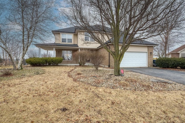traditional home featuring aphalt driveway, a garage, and brick siding