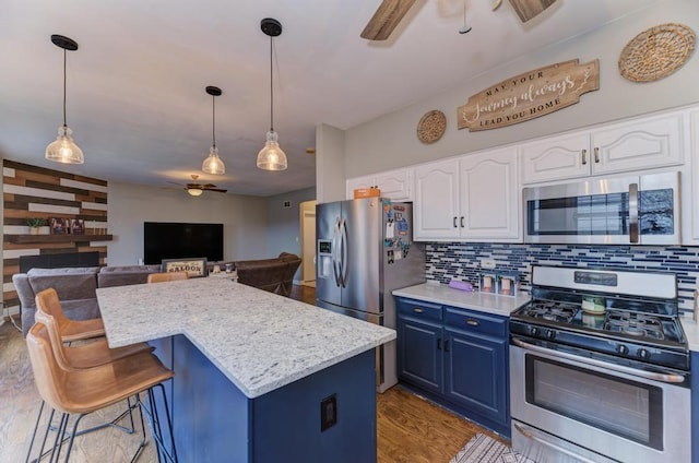 kitchen featuring ceiling fan, stainless steel appliances, decorative backsplash, blue cabinetry, and a kitchen island