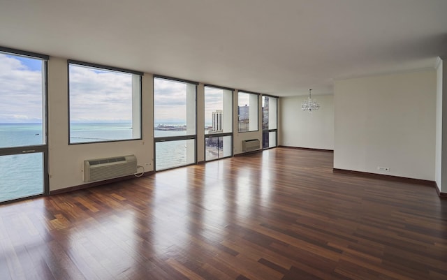 unfurnished room featuring a chandelier, a wall mounted air conditioner, wood finished floors, an AC wall unit, and a water view