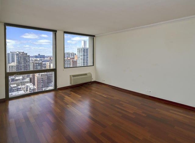 unfurnished room with a wall unit AC, wood finished floors, a view of city, baseboards, and ornamental molding