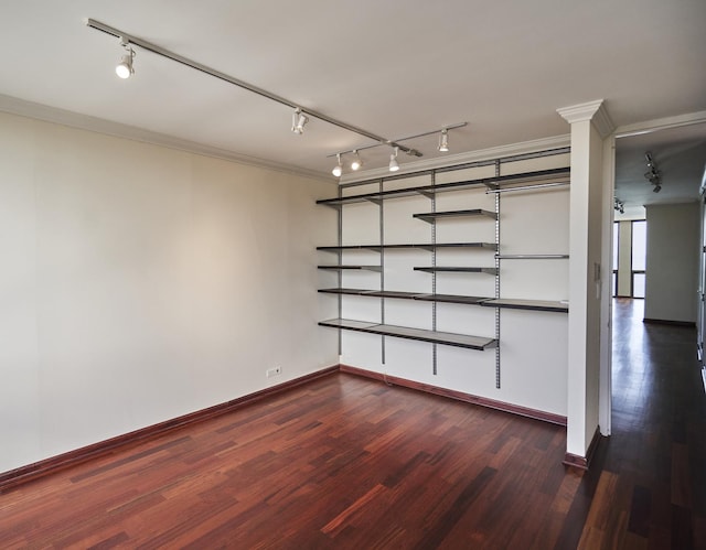 spare room with rail lighting, dark wood-style floors, baseboards, and crown molding