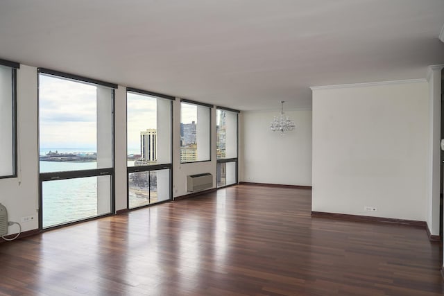 unfurnished room with a chandelier, a wall of windows, wood finished floors, baseboards, and ornamental molding