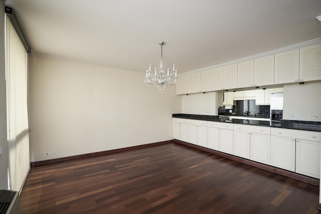 kitchen featuring dark wood finished floors, a chandelier, baseboards, tasteful backsplash, and dark countertops