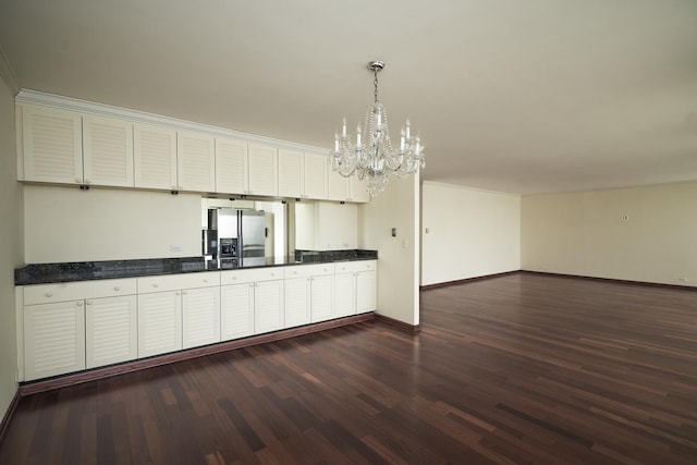 kitchen featuring stainless steel fridge, a chandelier, baseboards, dark wood finished floors, and dark countertops