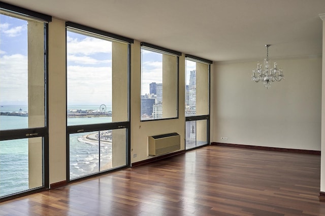 empty room with a chandelier, wood finished floors, a water view, baseboards, and floor to ceiling windows